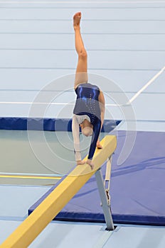Young gymnast girl performing routine on balance beam