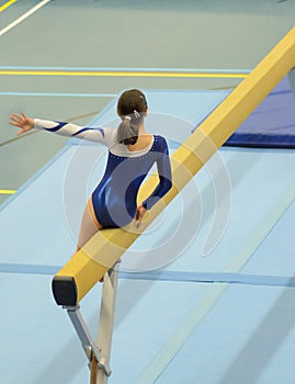 Young gymnast girl performing routine on balance beam