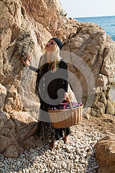 Young gypsy walking on the rocky beach