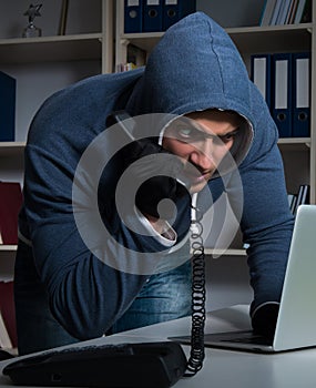 Young hacker hacking into computer at night