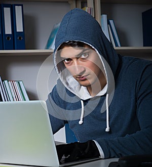 Young hacker hacking into computer at night