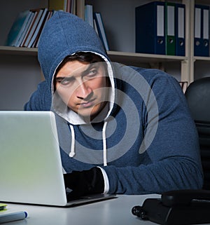 Young hacker hacking into computer at night