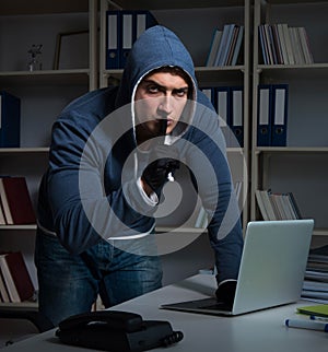 Young hacker hacking into computer at night