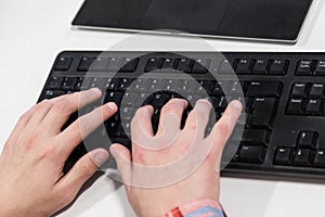 Young hacker typing code on computer keyboard