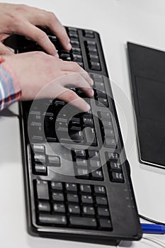 Young hacker typing code on computer keyboard