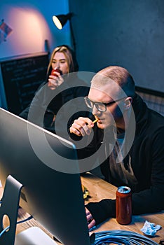 young hackers drinking beer and eating junk food while working