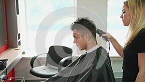 Young hair stylist shaves the back of the head of the client`s salon spa center