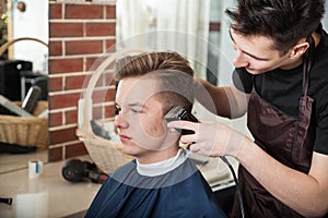 Young hairdresser trim hair to client in barber shop