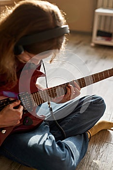 Young hairy man playing electric guitar at home