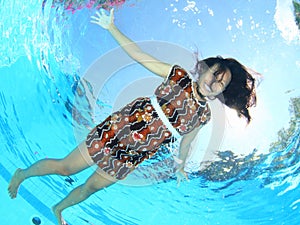 Laughing Papuan woman floating in pool in brown dress