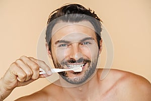 Young half-naked man smiling while brushing his teeth