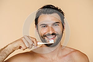 Young half-naked man smiling while brushing his teeth