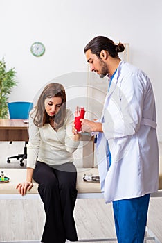 Young hand injured woman visiting male doctor traumatologist