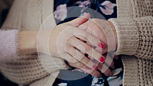 A young hand touches and holds an old wrinkled hand. Granddaughter holding a grandmother`s hand.