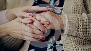 A young hand touches and holds an old wrinkled hand. Granddaughter holding a grandmother`s hand.