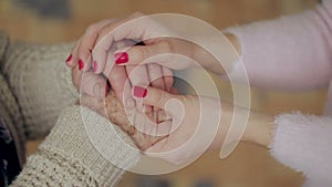 A young hand touches and holds an old wrinkled hand. Granddaughter holding a grandmother`s hand.