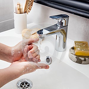 Young hands frothing with soap with beauty accessories on sink