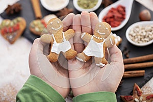 Young hands holding couple of gingerbread cookie people  - christmas sweets