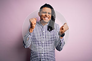 Young handsome african american afro man with dreadlocks wearing casual shirt excited for success with arms raised and eyes closed