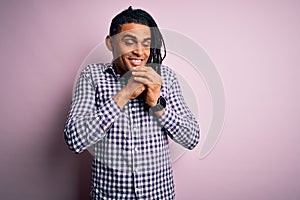 Young handsome african american afro man with dreadlocks wearing casual shirt laughing nervous and excited with hands on chin