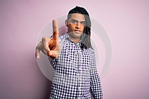 Young handsome african american afro man with dreadlocks wearing casual shirt Pointing with finger up and angry expression,