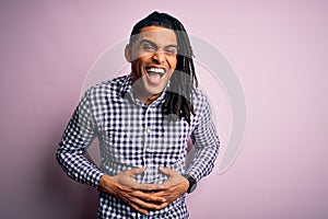 Young handsome african american afro man with dreadlocks wearing casual shirt smiling and laughing hard out loud because funny