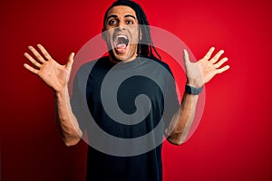 Young handsome african american afro man with dreadlocks wearing casual t-shirt celebrating crazy and amazed for success with arms