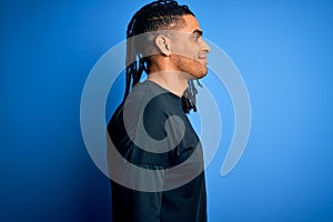 Young handsome african american afro man with dreadlocks wearing casual t-shirt looking to side, relax profile pose with natural