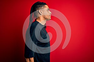 Young handsome african american afro man with dreadlocks wearing casual t-shirt looking to side, relax profile pose with natural