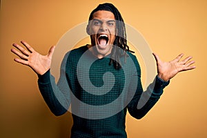 Young handsome african american afro man with dreadlocks wearing green casual sweater celebrating crazy and amazed for success