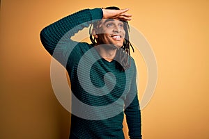 Young handsome african american afro man with dreadlocks wearing green casual sweater very happy and smiling looking far away with