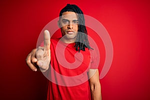 Young handsome african american afro man with dreadlocks wearing red casual t-shirt Pointing with finger up and angry expression,