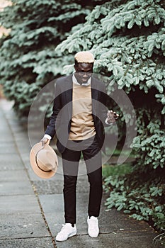 Young handsome african american businessman with hat walking in the city street