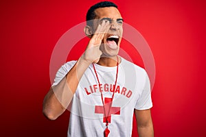 Young handsome african american lifeguard man wearing t-shirt with red cross and whistle shouting and screaming loud to side with