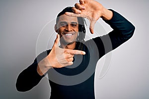 Young handsome african american man with dreadlocks wearing black casual sweater smiling making frame with hands and fingers with