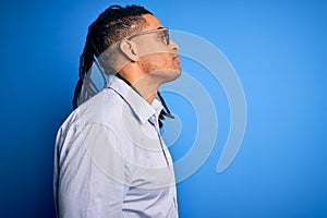 Young handsome african american man with dreadlocks wearing casual shirt and glasses looking to side, relax profile pose with