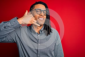 Young handsome african american man with dreadlocks wearing casual shirt and glasses smiling doing phone gesture with hand and