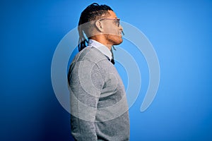 Young handsome african american man with dreadlocks wearing casual sweater and glasses looking to side, relax profile pose with