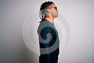 Young handsome african american man with dreadlocks wearing casual t-shirt and glasses looking to side, relax profile pose with