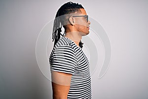 Young handsome african american man with dreadlocks wearing striped t-shirt and glasses looking to side, relax profile pose with