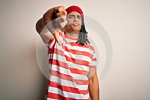 Young handsome african american man with dreadlocks wearing striped t-shirt and wool hat looking unhappy and angry showing