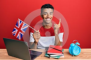 Young handsome african american man exchange student holding uk flag smiling with an idea or question pointing finger with happy