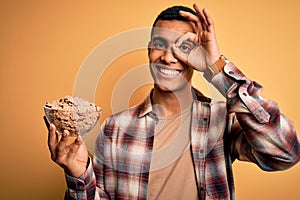 Young handsome african american man holding bowl with healthy cornflakes cereals with happy face smiling doing ok sign with hand