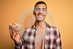 Young handsome african american man holding bowl with healthy cornflakes cereals with a happy face standing and smiling with a