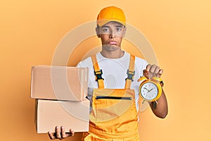 Young handsome african american man holding delivery box and alarm clock for express service depressed and worry for distress,