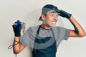 Young handsome african american man tattoo artist wearing professional uniform and gloves holding tattooer machine very happy and