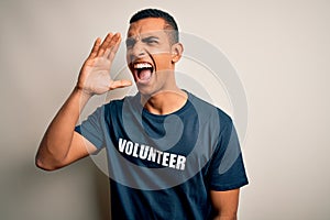 Young handsome african american man volunteering wearing t-shirt with volunteer message shouting and screaming loud to side with