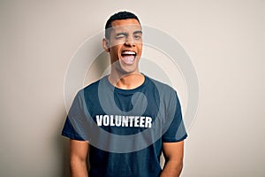 Young handsome african american man volunteering wearing t-shirt with volunteer message winking looking at the camera with sexy