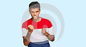 Young handsome african american man wearing casual clothes angry and mad raising fist frustrated and furious while shouting with