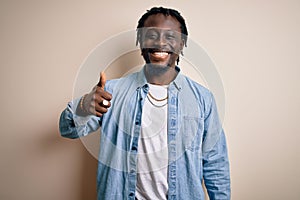 Young handsome african american man wearing casual denim shirt over white background doing happy thumbs up gesture with hand
